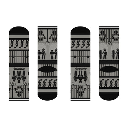 A pair of black and white crew socks with a geometric pattern, featuring designs that include cubes and what appears to be a representation of a police station or jail.