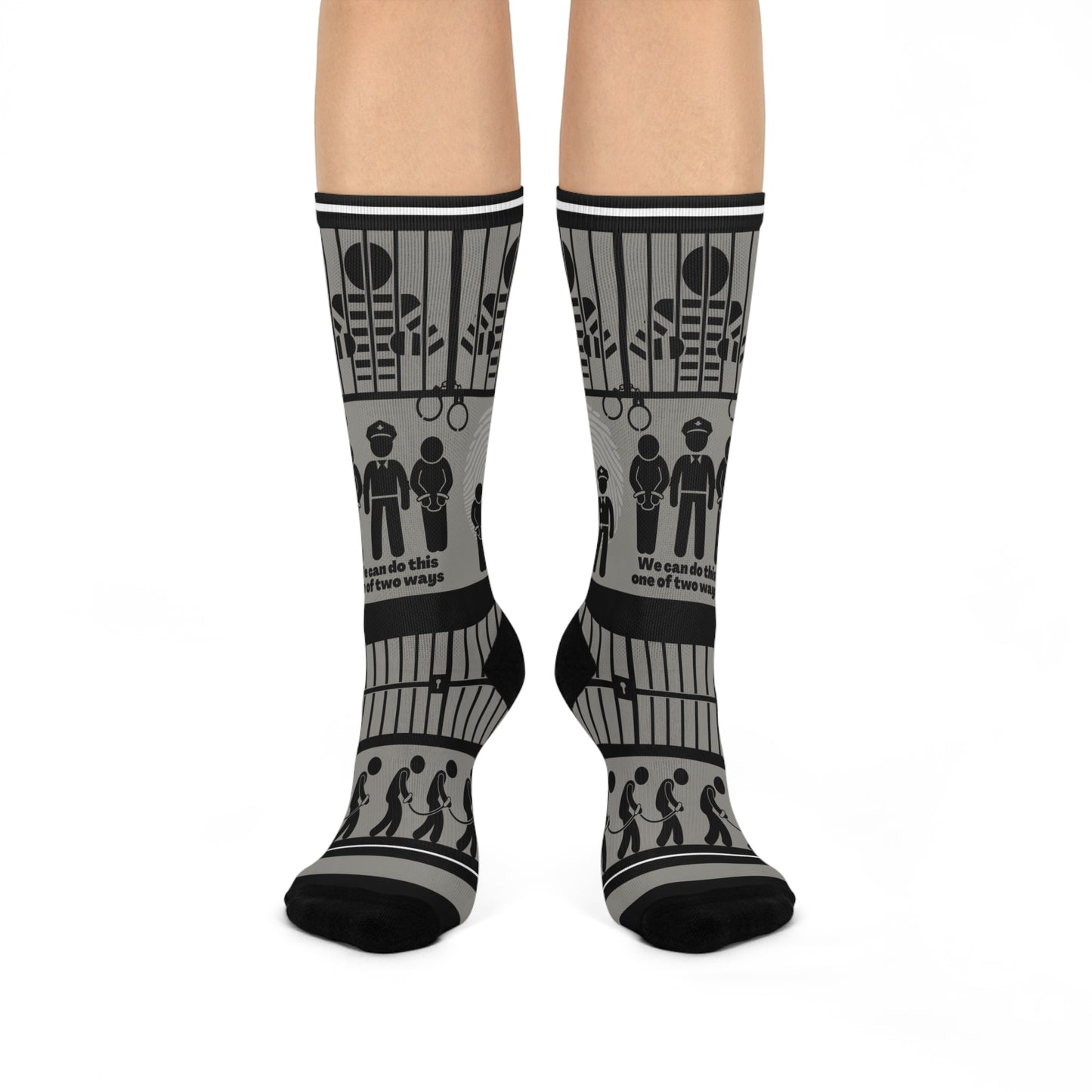 A pair of black and white crew socks with a geometric pattern, featuring designs that include cubes and what appears to be a representation of a police station or jail.
