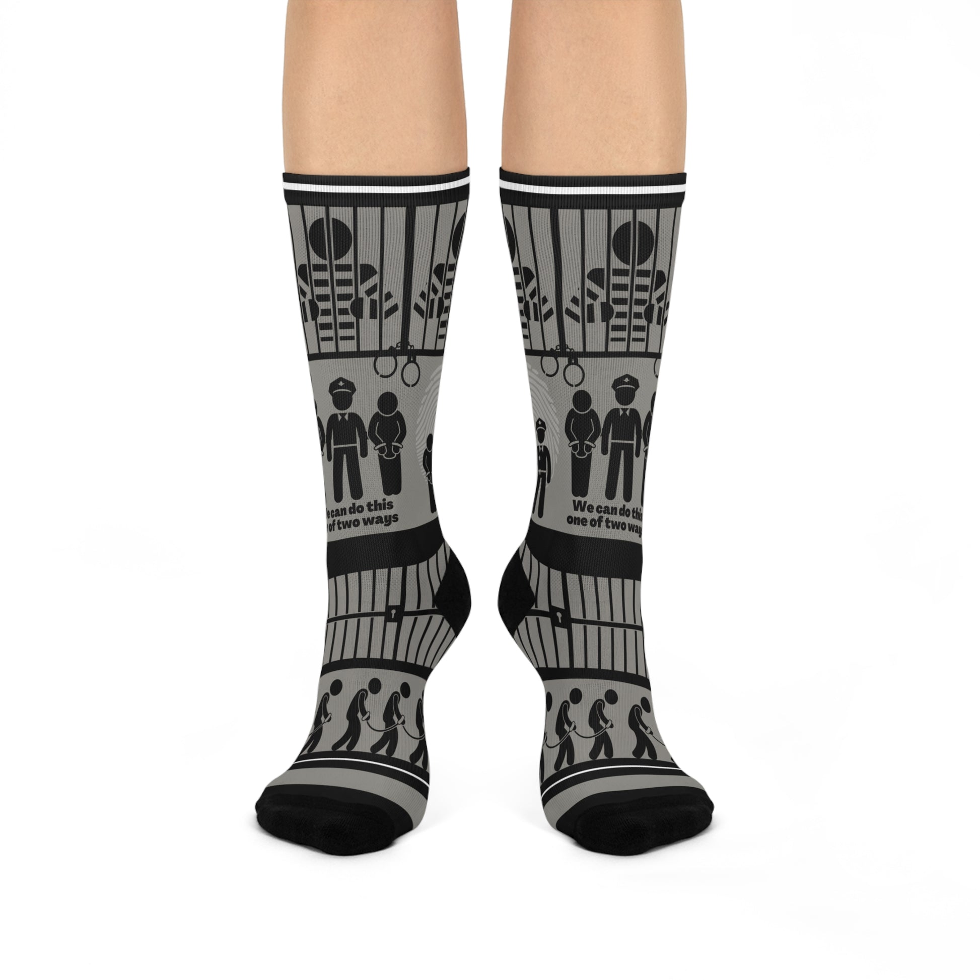 A pair of black and white crew socks with a geometric pattern, featuring designs that include cubes and what appears to be a representation of a police station or jail.